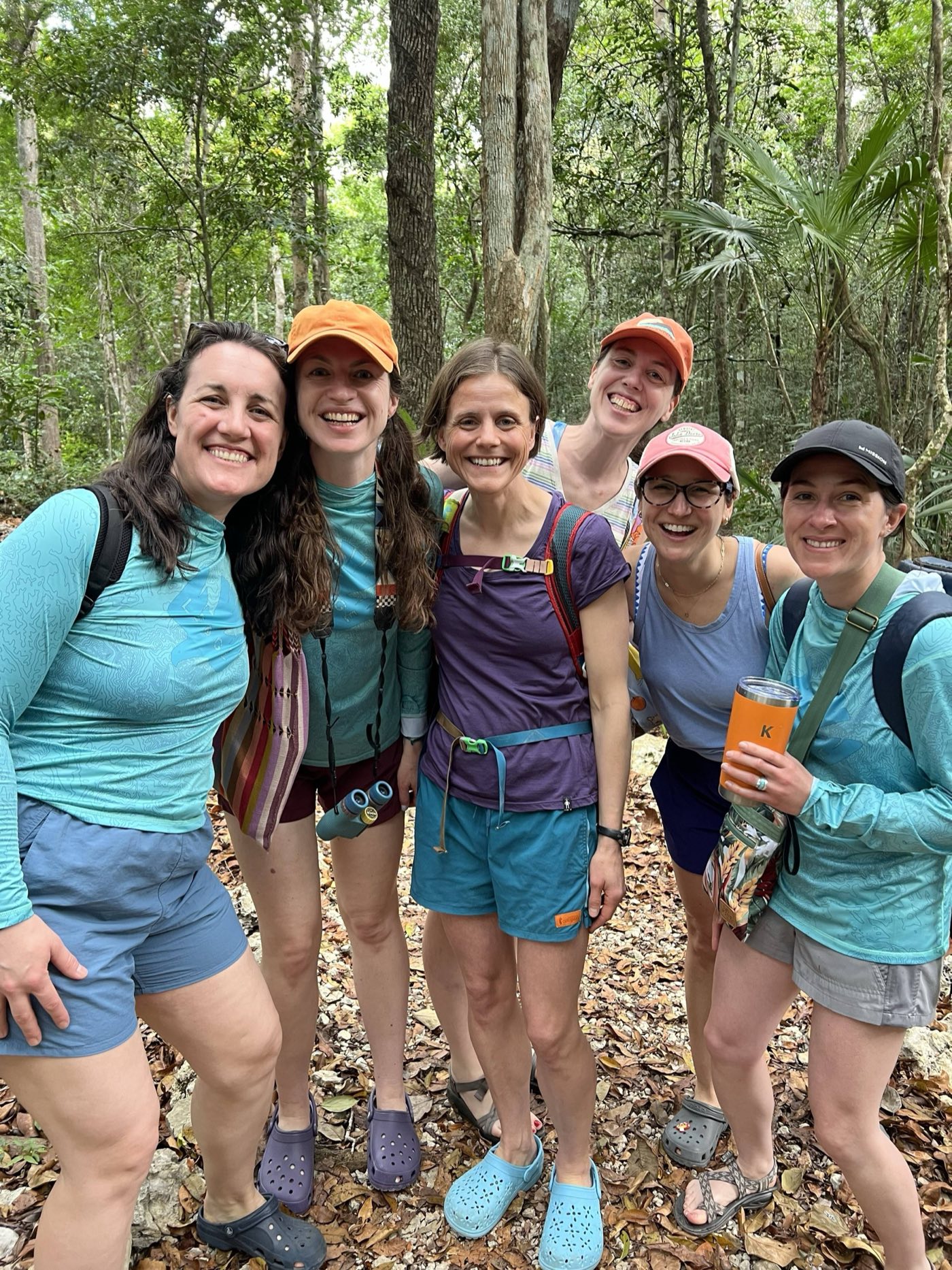 Group of six friends laughing together on a jungle trail near Tulum