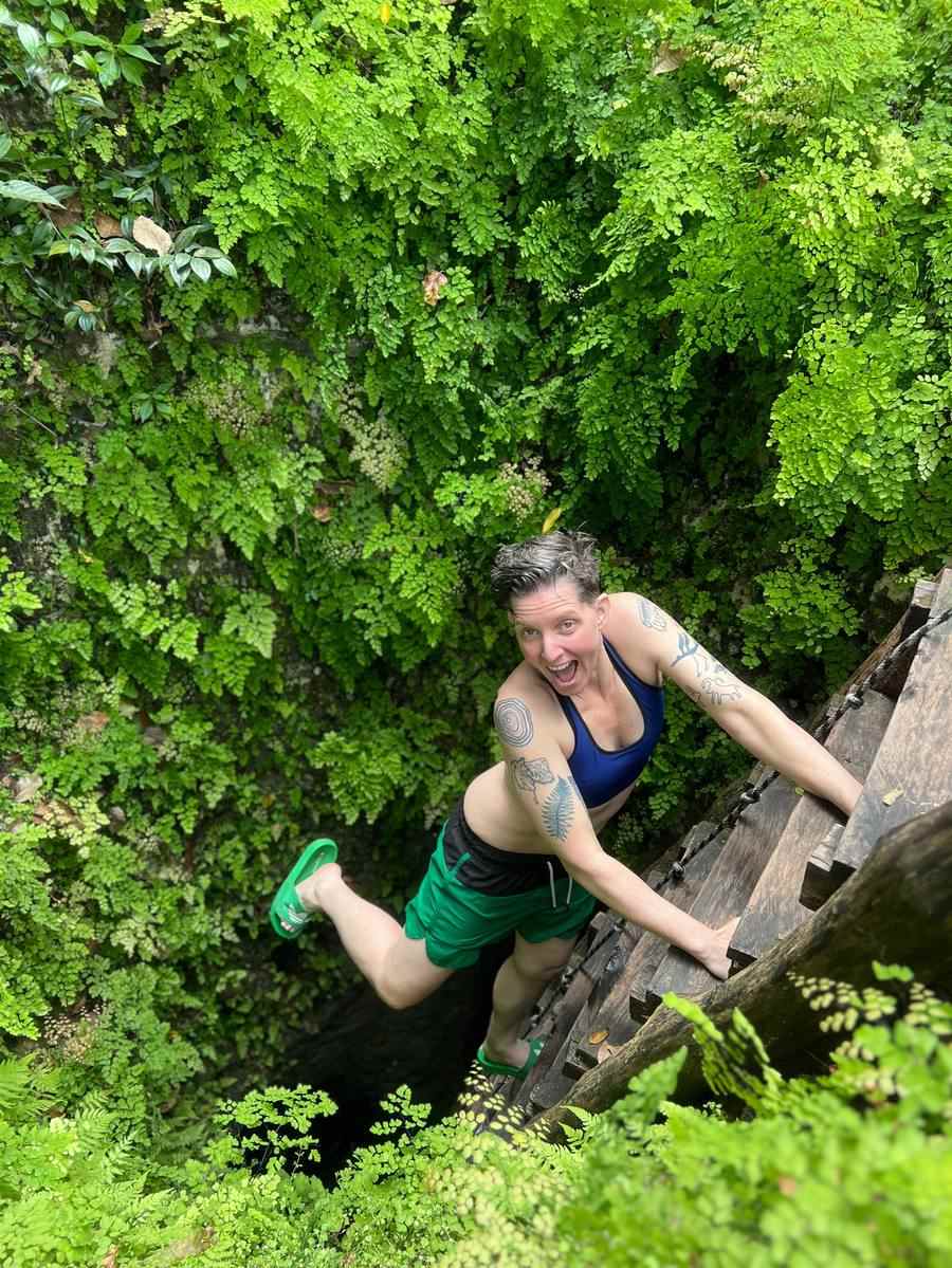 Guest laughing mid-descent into a secret cenote entrance near Tulum