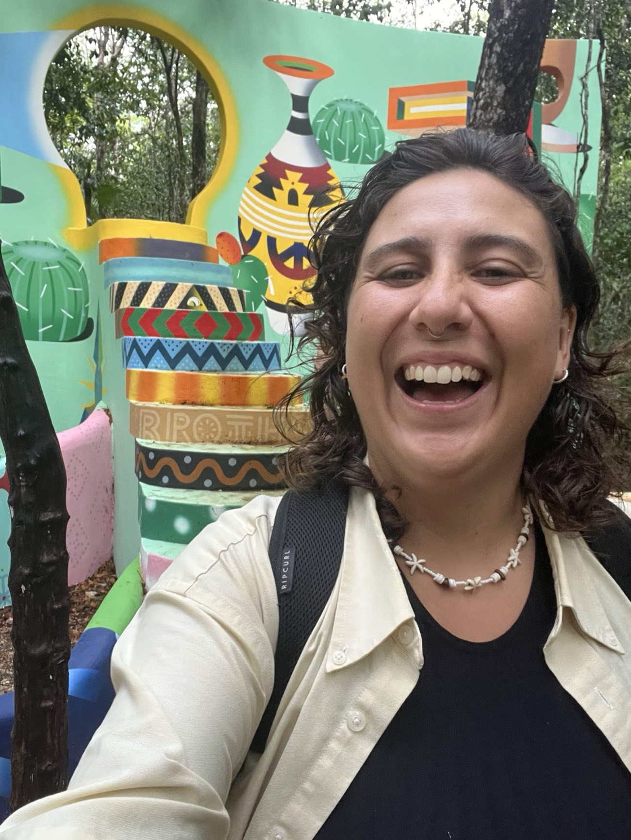 Guide laughing in front of a colorful mural in Tulum town