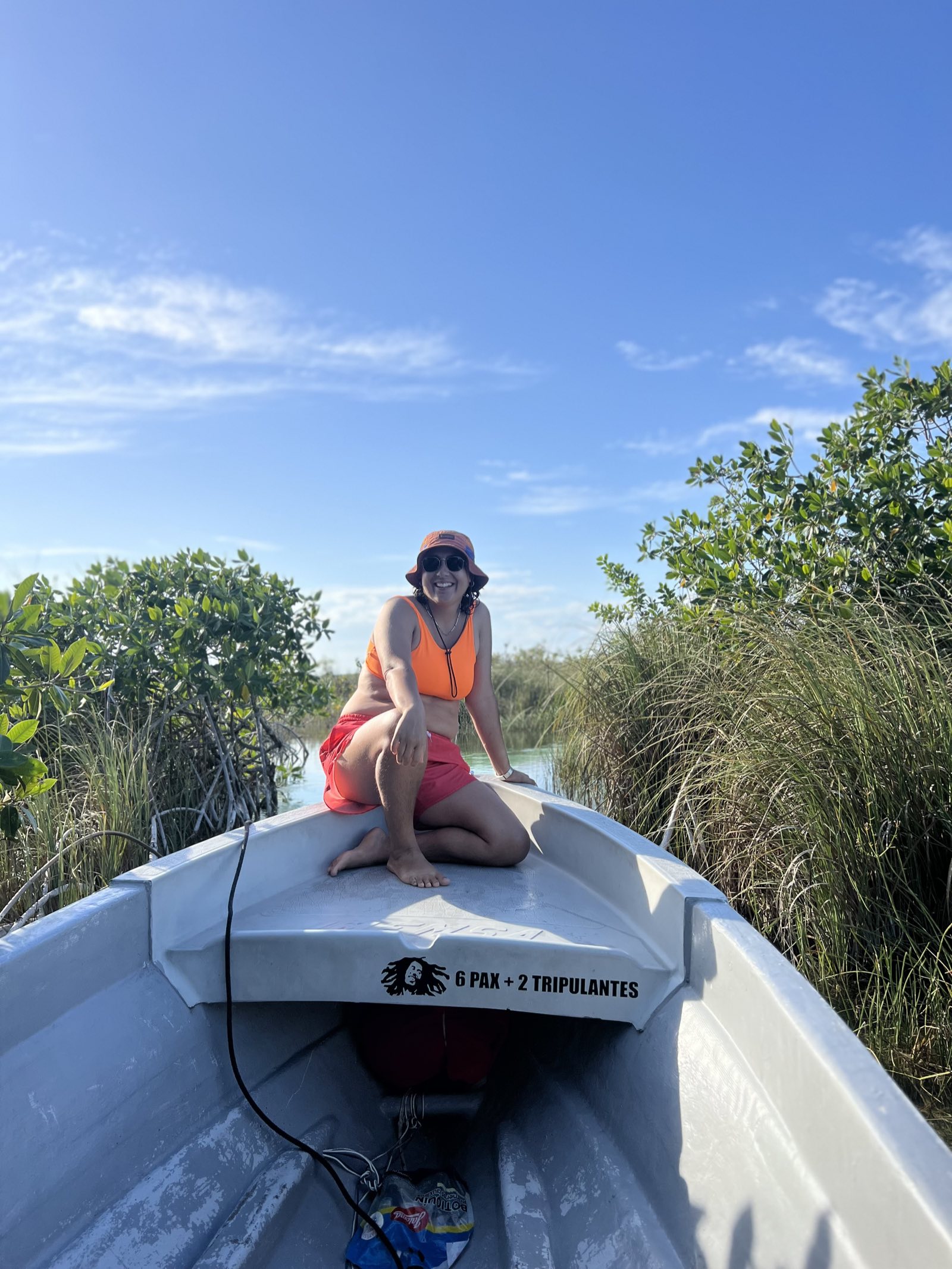 Camp Adventure Collective guide smiling on the bow of a boat through the mangroves near Tulum